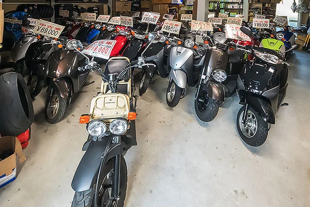 店内に整然と並ぶ中古スクーターの前方から見た展示風景