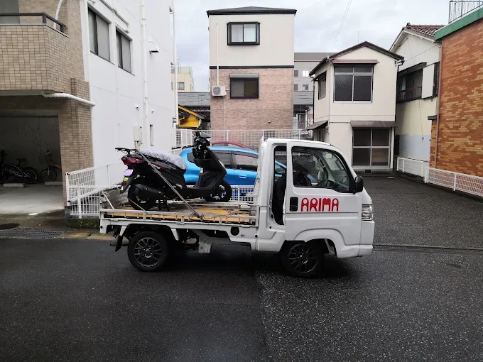 ARIMAロゴ入りの軽トラックにスクーターを積み込む様子